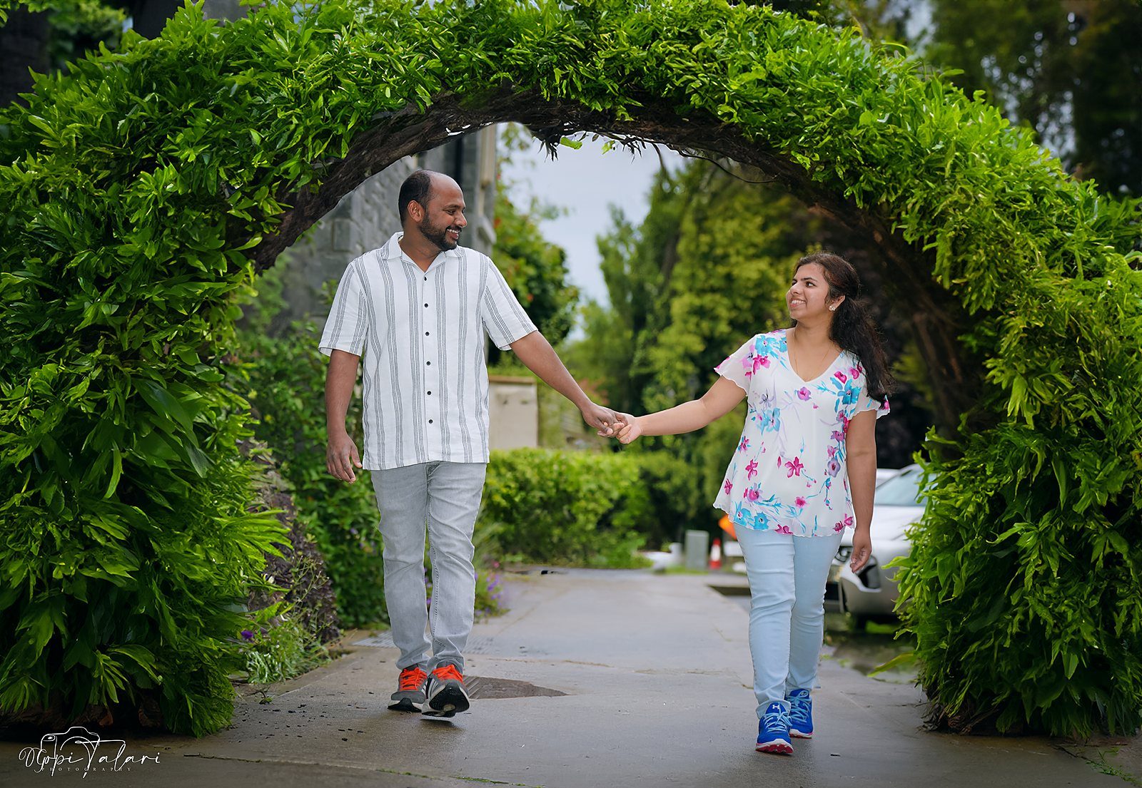 Couple walking through a green garden arch