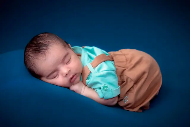 Newborn sleeping on navy fabric