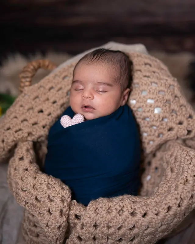 Newborn in knitted nest with bow