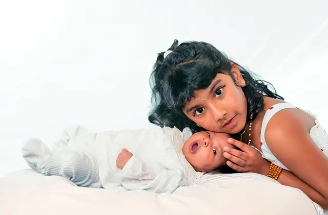 Big sister lying beside newborn