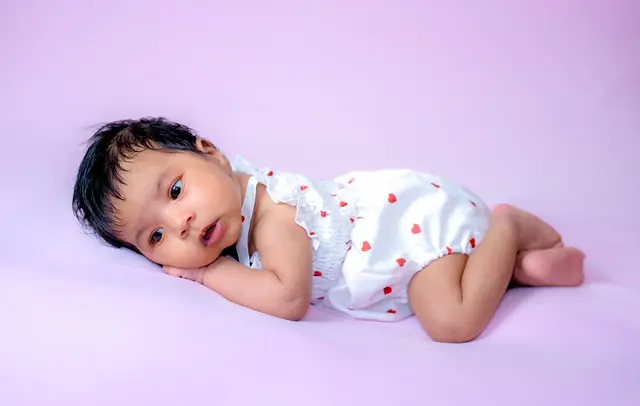 Baby girl on lilac backdrop