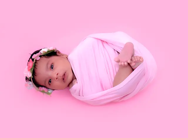 Newborn girl in pink wrap with floral headband