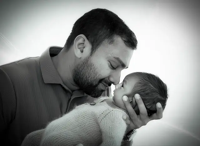 Father kissing newborn