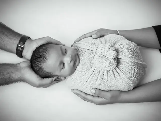 Wrapped newborn in hands, black and white