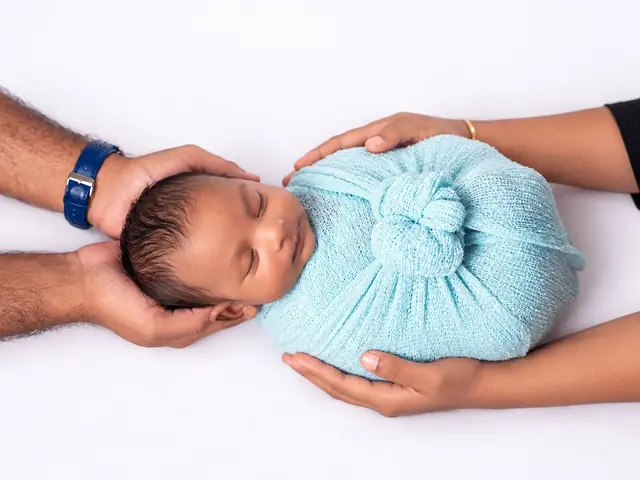 Newborn in blue wrap in parents' hands