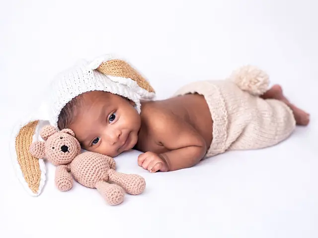 Newborn in bunny outfit with teddy