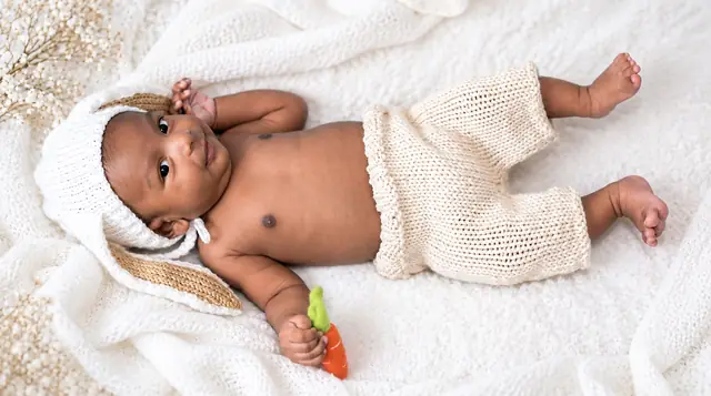 Newborn in knitted outfit on white