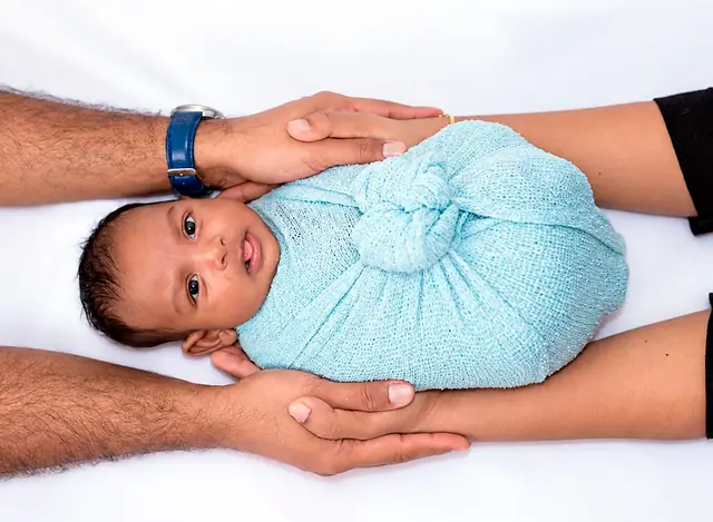 Newborn in blue wrap held by parents